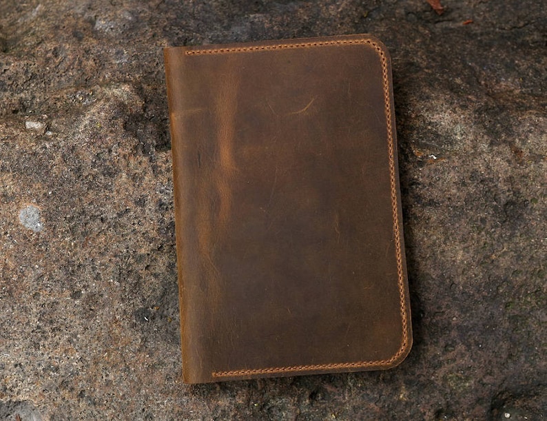 May include: A brown leather notebook with stitched edges.