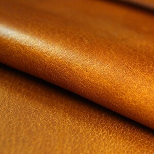 May include: Close-up of a folded piece of brown leather with a textured surface.