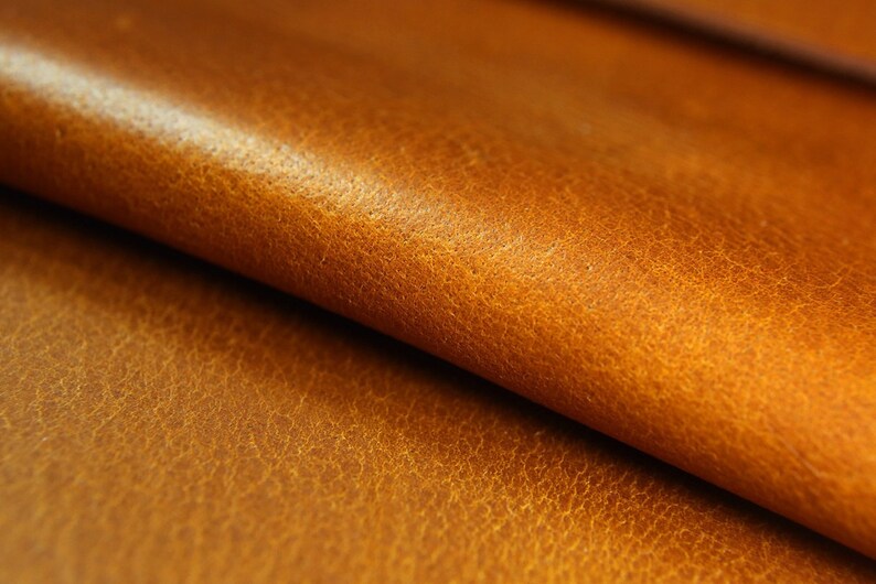 May include: Close-up of a folded piece of brown leather with a textured surface.