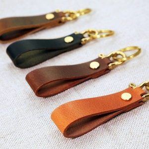 May include: Four leather keychains with brass key rings. The keychains are brown, black, dark brown, and light brown.