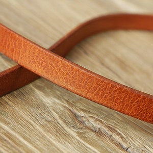 May include: Close-up of a brown leather strap with a textured surface.