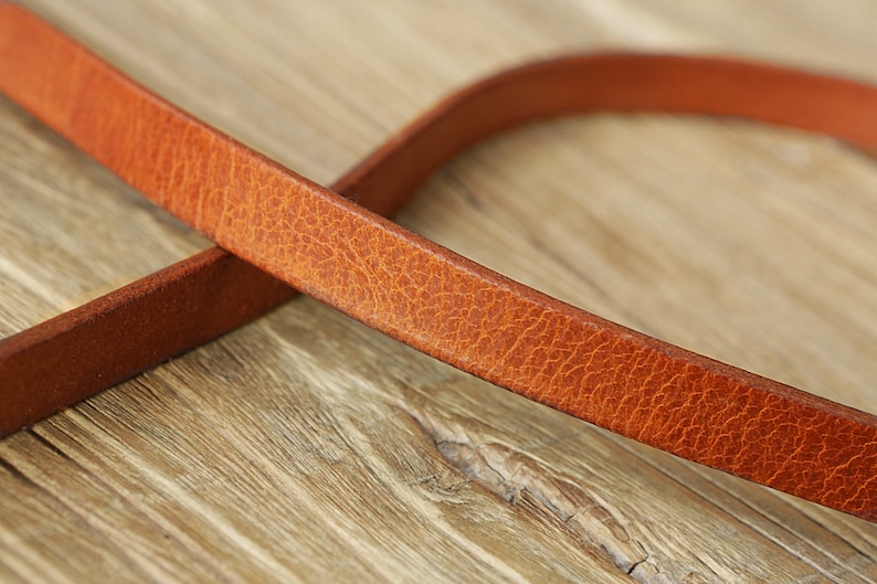 May include: Close-up of a brown leather strap with a textured surface.