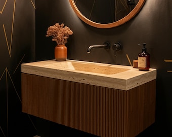 May include: A modern bathroom vanity with a travertine countertop and a brown wood cabinet with vertical grooves. The vanity has a rectangular sink and a black faucet. A small vase with dried flowers sits on the countertop.