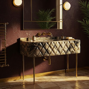 May include: A luxurious bathroom sink with a marble-like finish and a diamond pattern. The sink is supported by gold-colored legs and features a gold faucet. The background includes a mirror, wall sconces, and a patterned wallpaper.