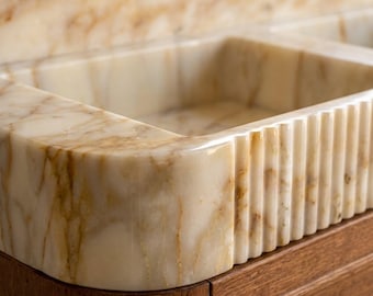 Lavabo de mármol Calacatta Gold estriado con protector contra salpicaduras y detalles tallados a mano para la remodelación de baños de lujo.
