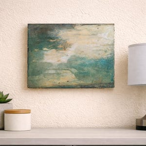 Puede incluir: Una taza de cerámica blanca con un asa negra y el texto "But First, Coffee" en un estilo manuscrito. La taza está sobre una superficie blanca. La taza mide aproximadamente 10 cm de alto.