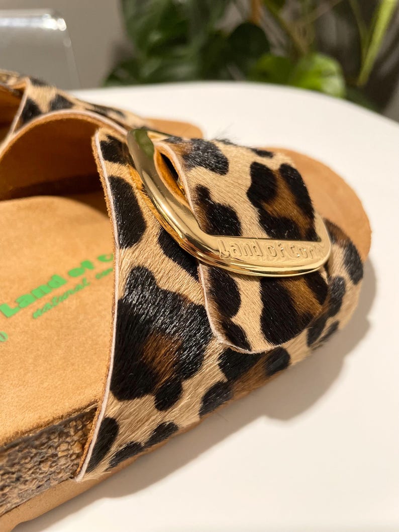 Pu&ograve; includere: Sandali con stampa leopardata con fibbia dorata e il nome del marchio "Band of Cowgirls" in rilievo sulla fibbia.