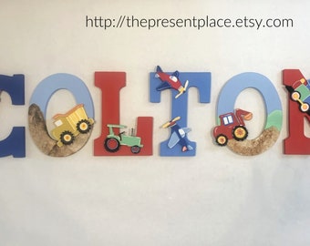 Letras de madera para niños con un camión de bomberos, aviones, un tren, un tractor, un camión volquete y una excavadora