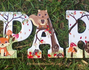 May include: Wooden letters spelling "PARK" painted in white with woodland animal and nature scenes. The letter "P" features a fox, the letter "A" features a squirrel, and the letter "R" features a hedgehog.