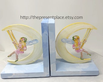 fairy bookends with a fairy swinging on a moon