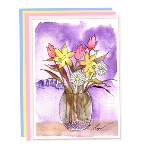 K&ouml;nnte beinhalten: Aquarell-Gru&szlig;karte mit einem Blumenstrau&szlig; in einer durchsichtigen Glasvase. Das Arrangement umfasst gelbe Narzissen, rosa Tulpen und wei&szlig;e G&auml;nsebl&uuml;mchen vor einem lila Hintergrund. Die Karte hat einen wei&szlig;en Rand mit pastellblauen, rosa und gelben Schichten.