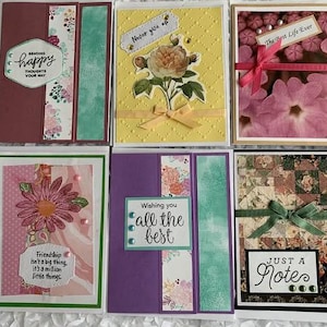 May include: A collection of handmade greeting cards with various designs. One card features the text "Sending happy thoughts your way." Another says "Never give up." Other cards have floral designs and the text "The Best Life Ever," "Friendship isn't a big thing," and "Just a Notes."