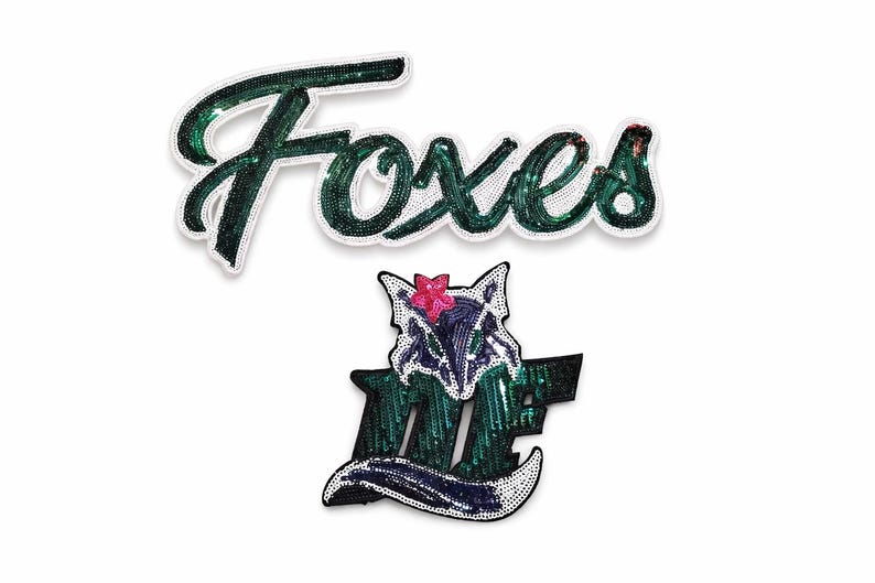 K&ouml;nnte beinhalten: Zwei Pailletten-Patches auf wei&szlig;em Hintergrund. Der obere Patch buchstabiert "Foxes" in einer kursiven Schriftart mit gr&uuml;nen Pailletten und einem wei&szlig;en Rand. Der untere Patch ist ein Fuchsmotiv mit einer rosa Blume und den Buchstaben "MF".