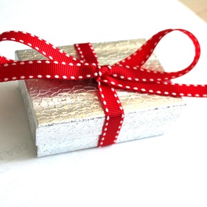 May include: A small silver gift box with a red ribbon with white polka dots tied in a bow.