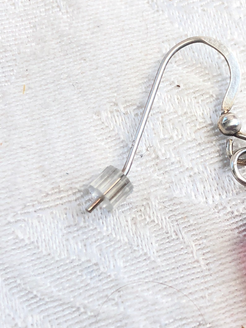 May include: Silver earring hook with a clear plastic stopper.