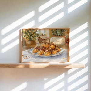 May include: A watercolour painting in a wooden frame, depicting a plate of eclairs topped with chocolate and almonds. The plate sits on a table with a white cloth. The background shows a dining room with plants and sunlight.