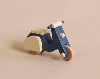 May include: A blue and cream wooden toy scooter with a rounded seat and wooden wheels.