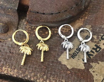 May include: Two pairs of earrings with palm tree charms. One pair is gold and the other is silver.