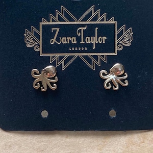 May include: Gold octopus stud earrings on a black card with the text "Zara Taylor London" in white.