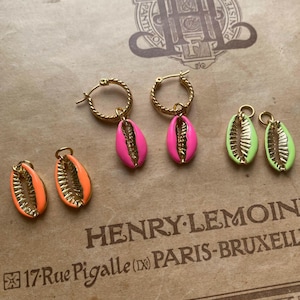 Op de afbeelding: Gouden oorringen met schelphangers in neonroze, oranje en groen. De oorbellen worden getoond op een vintage document met Franse tekst.