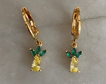 以下が含まれることがあります： 黄緑色のキュービックジルコニアでできたパイナップルのチャームがついた、ゴールドのフープピアスのペアです。