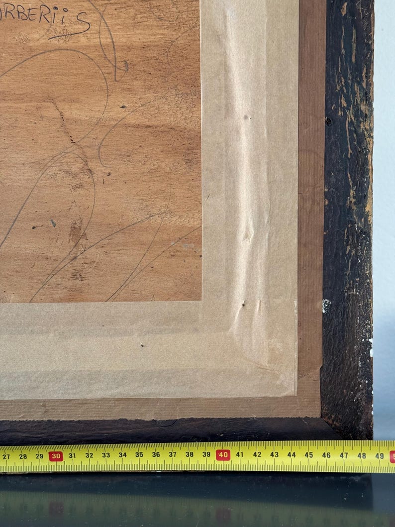Puede incluir: Primer plano de un marco de madera con un respaldo de papel marr&oacute;n. Una cinta m&eacute;trica amarilla se coloca en la parte inferior del marco, con los n&uacute;meros del 27 al 49 visibles. El texto "RBERIS" est&aacute; escrito con tinta negra en el marco de madera.