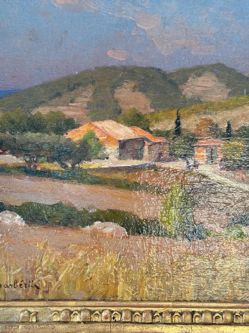 Puede incluir: Una pintura de un paisaje rural con una peque&ntilde;a casa en la distancia. La casa est&aacute; rodeada de &aacute;rboles y colinas. El cielo es de un azul claro con algunas nubes. La pintura est&aacute; firmada "anl&eacute;tin" en la esquina inferior izquierda.