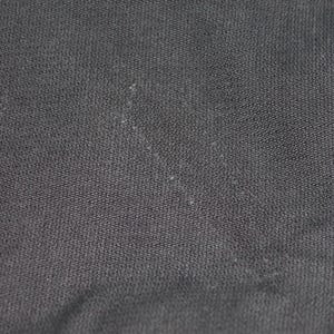May include: A close-up view of a solid black fabric with a visible woven texture. The material features a consistent dark charcoal to black color throughout, displaying a tight, uniform weave pattern with subtle light-colored lint particles.