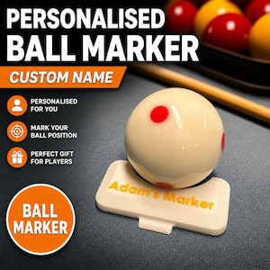 May include: A personalized ball marker with the text "Adam's Marker" in yellow. The marker is white and holds a billiard ball with red dots. The image includes text that says "Personalised Ball Marker" and "Custom Name".
