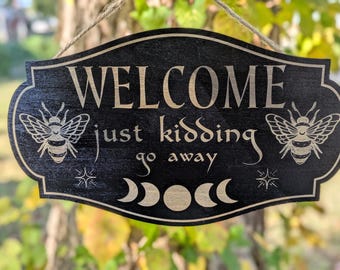 Funny Welcome Sign - “Welcome Just Kidding Go Away” - Laser Engraved Wooden Door Sign with Bees & Moon Phases, Gothic Cottagecore Home Decor
