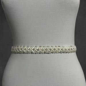 Handcrafted bridal belt adorned with sparkling crystals and pearls, designed to add elegance to your wedding gown. Delicate beadwork and intricate details make it a perfect accessory for a timeless bridal look.