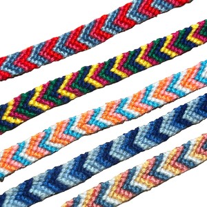 Op de afbeelding: Vijf geweven vriendschapsarmbanden diagonaal gerangschikt, elk met een duidelijk chevronpatroon. De banden tonen verschillende kleurencombinaties met rode, blauwe, gele, groene, oranje, roze en witte draden in een strakke, geknoopte textuur.