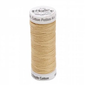 May include: A spool of light tan Sulky Cotton Petites thread. The white plastic top features a barcode and the text Sulky 712-1070 Cotton Petites Art 712. The bottom white plastic base is printed with the text Staple Cotton.