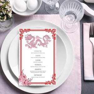 Peut inclure: Un menu rose et blanc avec une bordure rouge représentant un dragon rose. Le menu liste les éléments suivants : Cocktail, Amuse, Voor, Tussen, Hoofd, Dessert.