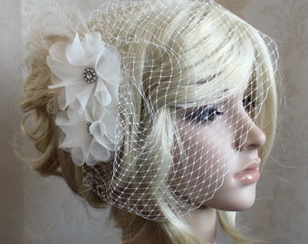 May include: A white bridal veil with a delicate floral hair comb featuring white fabric flowers and a rhinestone embellishment.