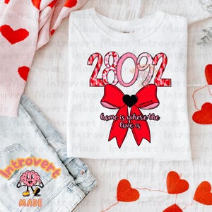 May include: White t-shirt with a pink and red heart design that says "2802" and "home is where the love is".