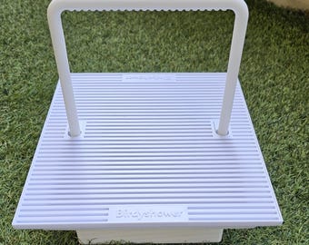 May include: A white square platform with a ribbed surface and a tall, arched handle featuring a scalloped underside. The word Birdyshower is embossed on the front edge of the platform, which is constructed from a solid, matte white material.