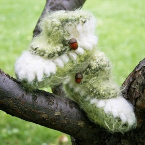 May include: A pair of green and white fuzzy crocheted boot cuffs with acorn embellishments.