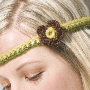 May include: A green and white crocheted headband with a brown and yellow crocheted flower accent.