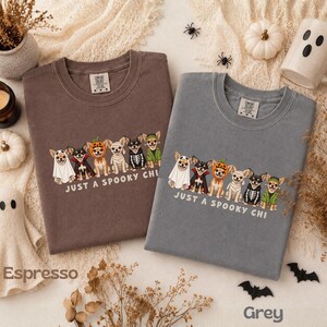 May include: Two crewneck t-shirts in espresso and grey, each featuring a graphic of six Chihuahuas in various Halloween costumes, including a ghost, vampire, pumpkin, mummy, skeleton, and witch, with the text "JUST A SPOOKY CHI" printed below.