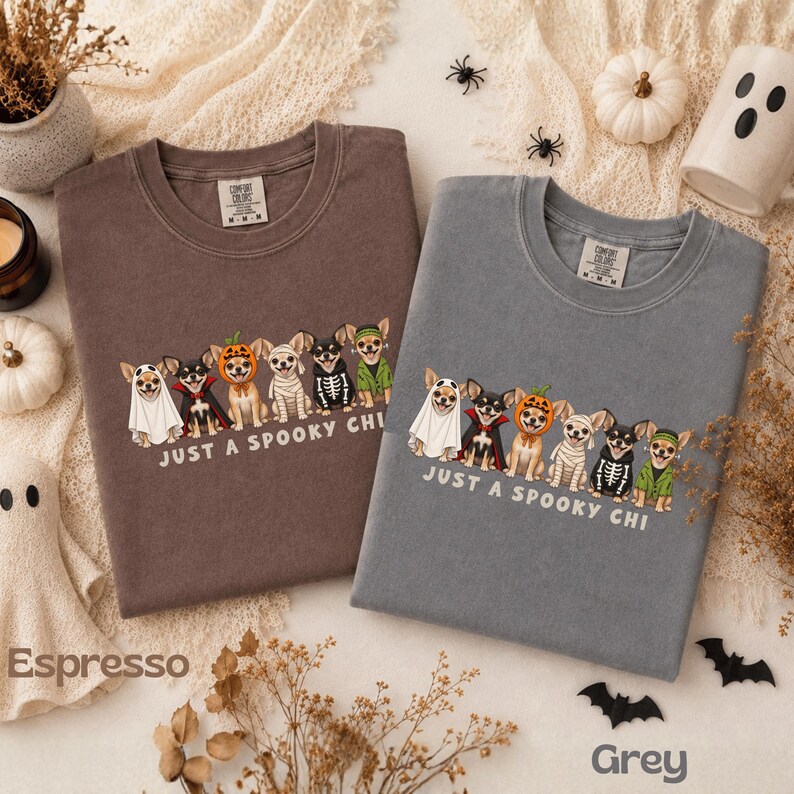 May include: Two crewneck t-shirts in espresso and grey, each featuring a graphic of six Chihuahuas in various Halloween costumes, including a ghost, vampire, pumpkin, mummy, skeleton, and witch, with the text "JUST A SPOOKY CHI" printed below.