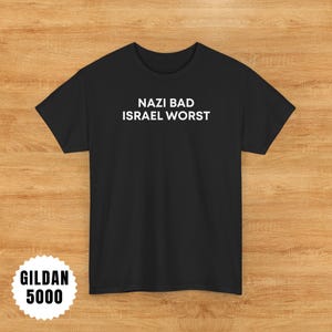May include: Black t-shirt with the white text "NAZI BAD ISRAEL WORST". The shirt is a Gildan 5000 model. The shirt is displayed on a wooden surface.