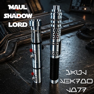 May include: Two metallic lightsabers with intricate designs. One has a perforated body with a black grip, the other has a segmented design with red accents. The text "MAUL SHADOW LORD" and "AKUN NEK700 JO77" are visible.
