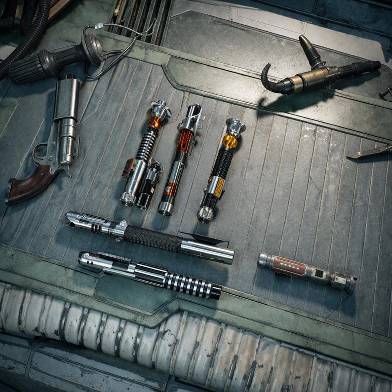 May include: A collection of various lightsabers and a blaster pistol are displayed on a metallic surface. The lightsabers feature diverse designs with silver, black, and red accents. The pistol has a silver body and a brown grip.