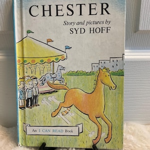 Puede incluir: Un libro infantil vintage titulado "CHESTER" de Syd Hoff. La portada presenta una ilustración de dibujos animados de un caballo corriendo, un tiovivo y niños. El libro forma parte de la serie "An I CAN READ Book".