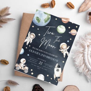 Op de afbeelding: Een blauwe en zwarte ruimte-thema verjaardagsuitnodiging met een raket, planeten en sterren. De tekst luidt "Two the Moon" en "Please join us to celebrate Oliver's 2nd Birthday".
