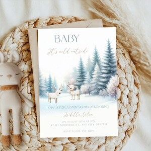 Op de afbeelding: Een uitnodiging voor een babyshower met een winterthema. De uitnodiging toont een aquarel illustratie van een besneeuwd bos met twee herten. Tekst bevat "BABY", "It's cold outside" en evenement details.