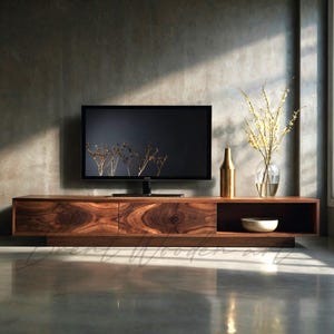 Può includere: Un mobile porta TV in legno lungo e basso con una ricca venatura marrone scuro, dotato di due scomparti chiusi e un ripiano aperto. Un televisore a schermo piatto è posizionato sopra, accompagnato da un vaso color oro e un vaso in vetro.