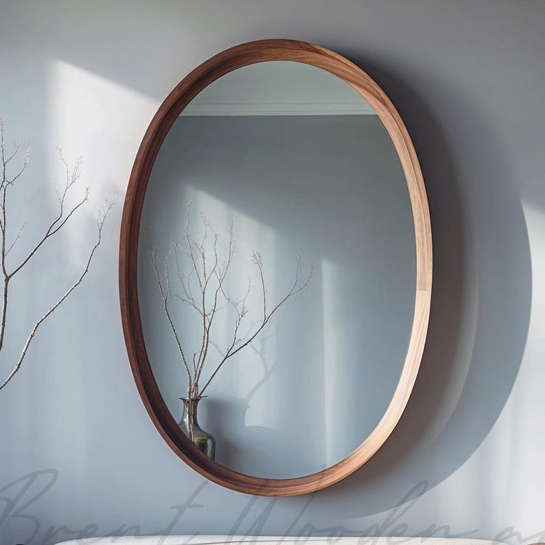May include: A large, oval-shaped mirror with a natural wood frame. The mirror is hanging on a light blue wall.