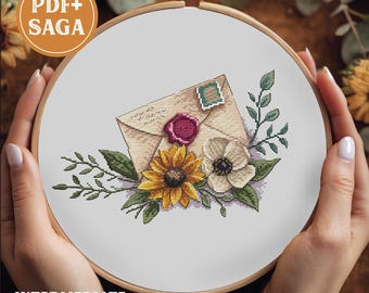 Puede incluir: Bastidor de bordado de punto de cruz con un diseño de sobre vintage con sello de cera, sello postal y arreglo floral. El diseño incluye un girasol, anémona y vegetación. Los textos "PDF+ SAGA" e "INTERMEDIATE" son visibles.